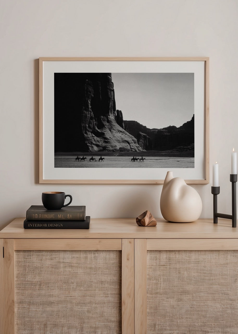 Vintage black and white poster of riders in a desert landscape.