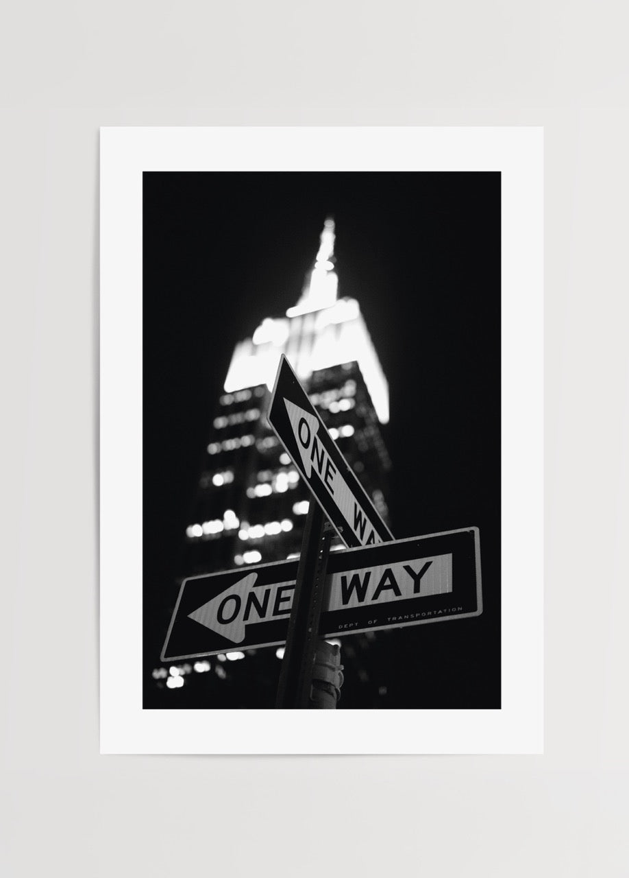 Black and white poster featuring New York street signs and skyline at night.