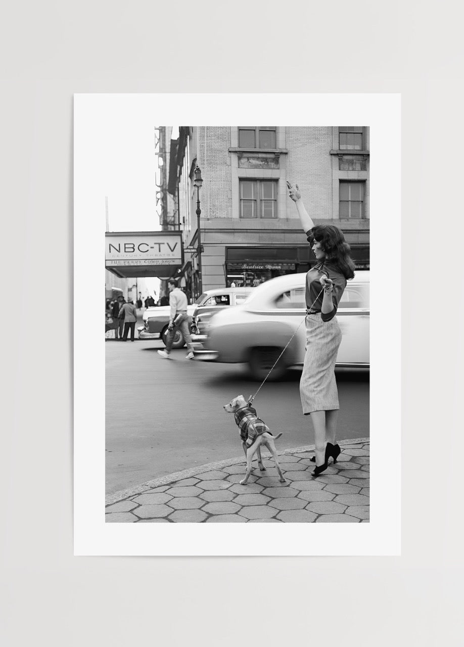 A vintage black and white photograph of a woman with a dog in NYC.