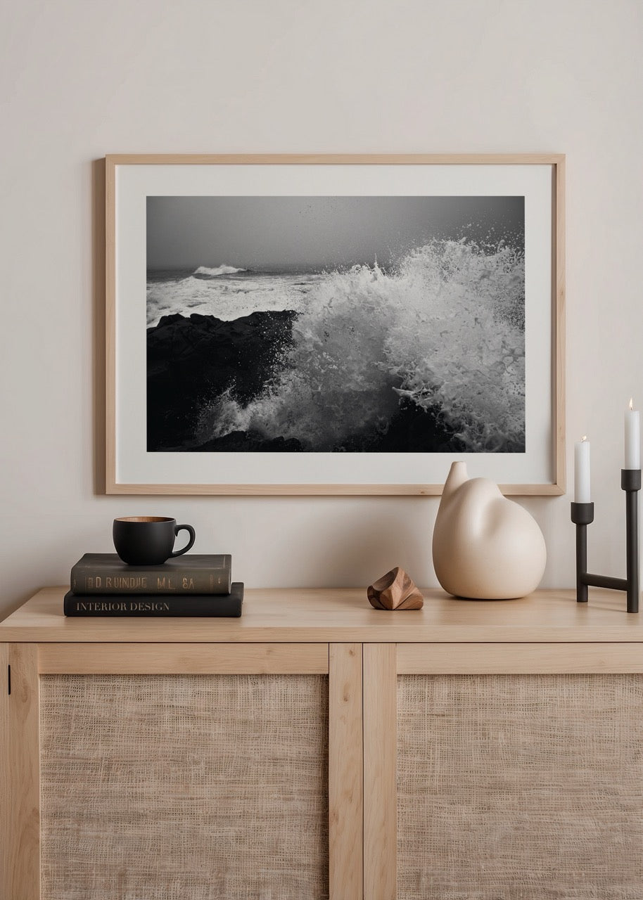 Black and white artwork of crashing waves on rocky shore
