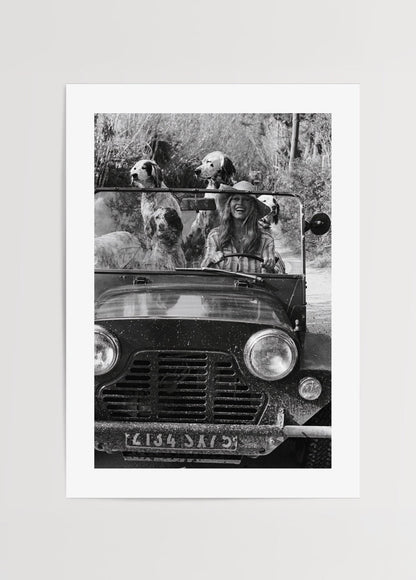 Black and white wall art of a joyful girl driving with dogs.