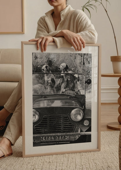 Black and white wall art of a joyful girl driving with dogs.