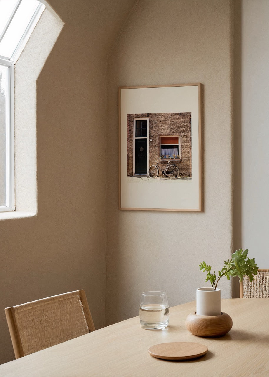 Photograph of a bicycle leaning against a brick wall with a door and window.