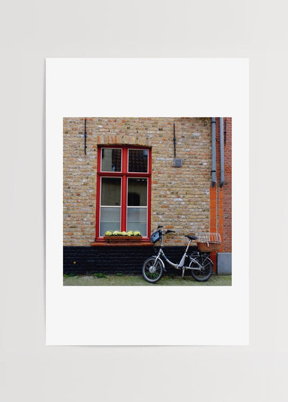 A bicycle beside a window in a charming Brussels brick wall setting.
