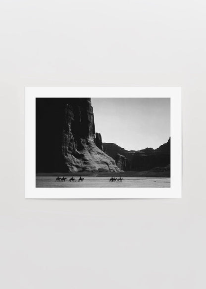 Vintage black and white poster of riders in a desert landscape.