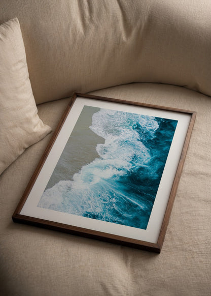 Aerial view of ocean waves merging with sandy shore in vibrant blue tones.