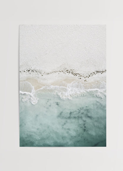 Aerial view of tranquil shoreline with soft sand and blue waves.