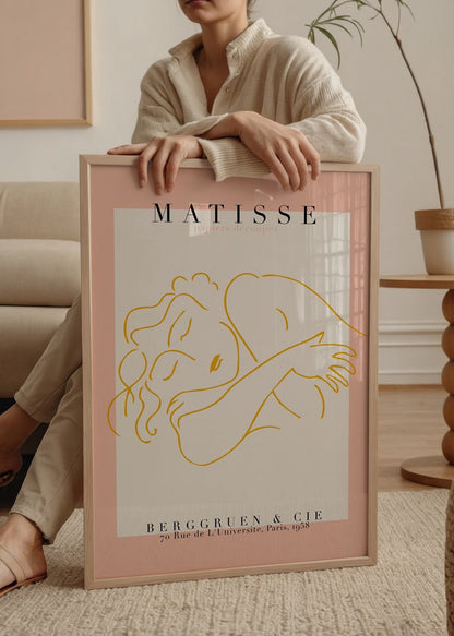 A minimalist art print featuring a serene embrace in yellow on a pink background.