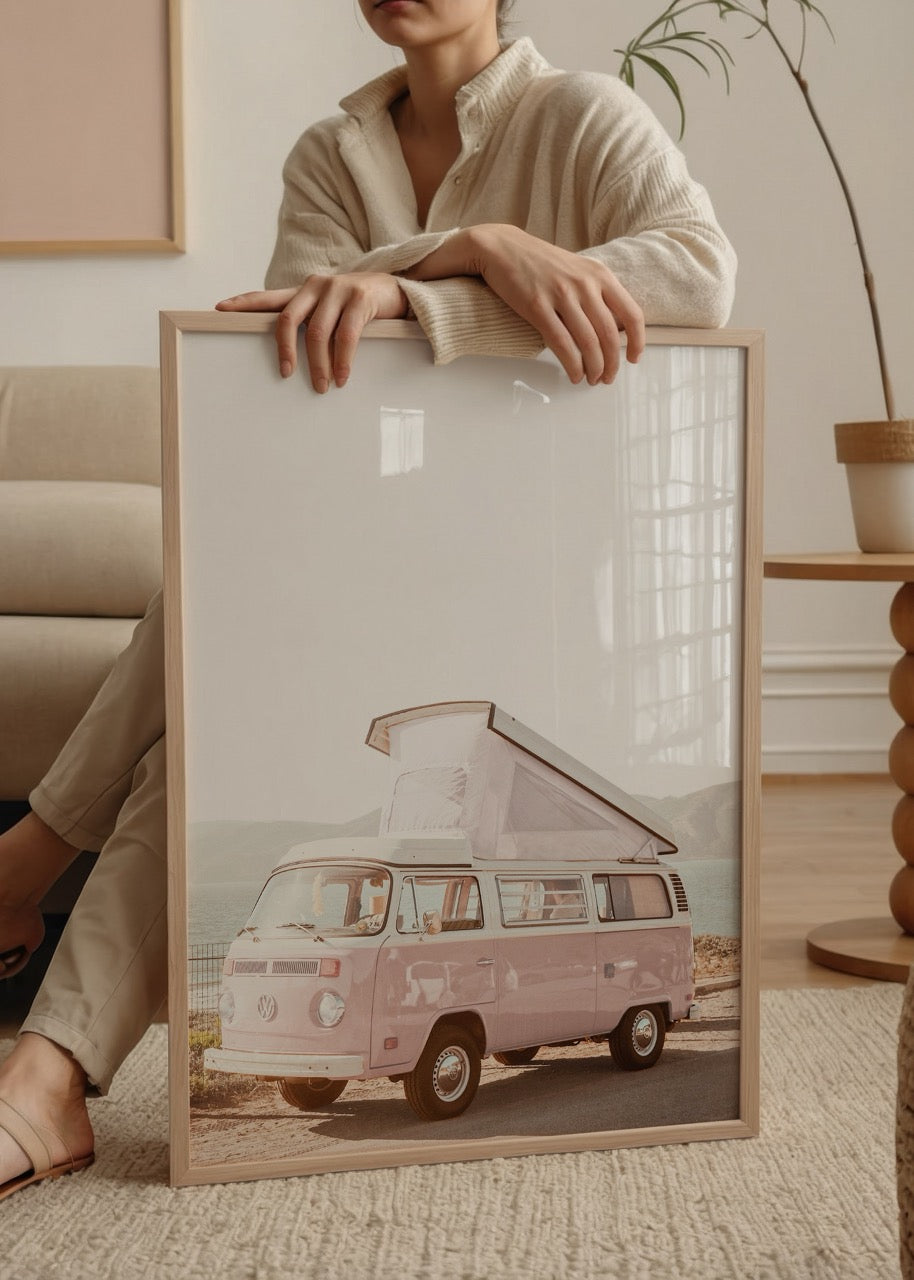 A whimsical pink caravan parked by the water, evoking adventure and nostalgia.