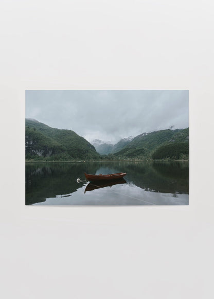 Art print of a tranquil lake with a solitary boat amidst mountains, perfect for wall decor.