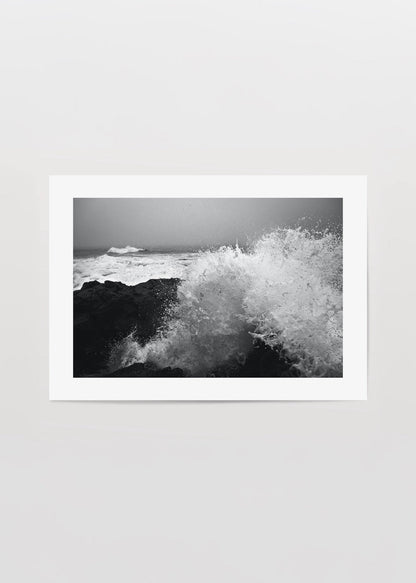Black and white artwork of crashing waves on rocky shore