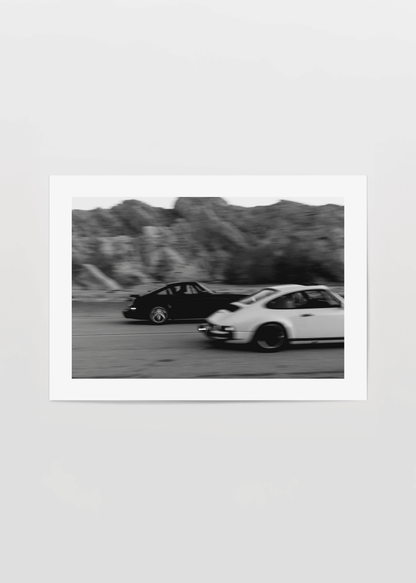 Vintage racing cars captured in dynamic motion artwork.