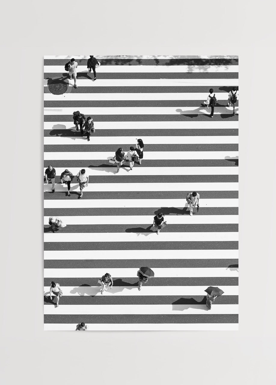 Black and white photograph of pedestrians crossing bold stripes.