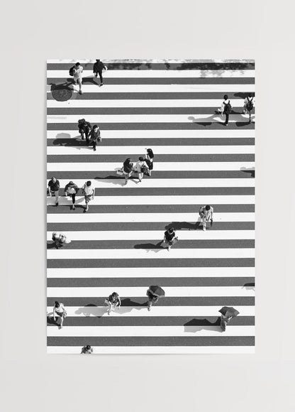 Black and white photograph of pedestrians crossing bold stripes.